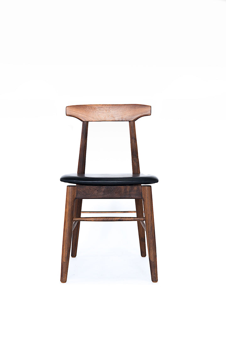 The Earl Home SABLE Dining Chair features a hand-made, black wooden design with a curved backrest and four legs. Its flat seat exemplifies minimalist elegance, crafted from solid wood for lasting durability.