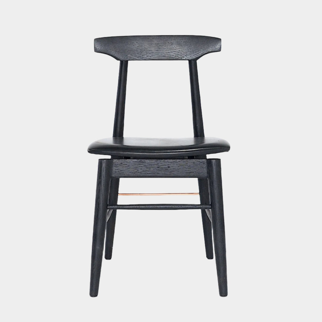 The Earl Home SABLE Dining Chair features a hand-made, black wooden design with a curved backrest and four legs. Its flat seat exemplifies minimalist elegance, crafted from solid wood for lasting durability.