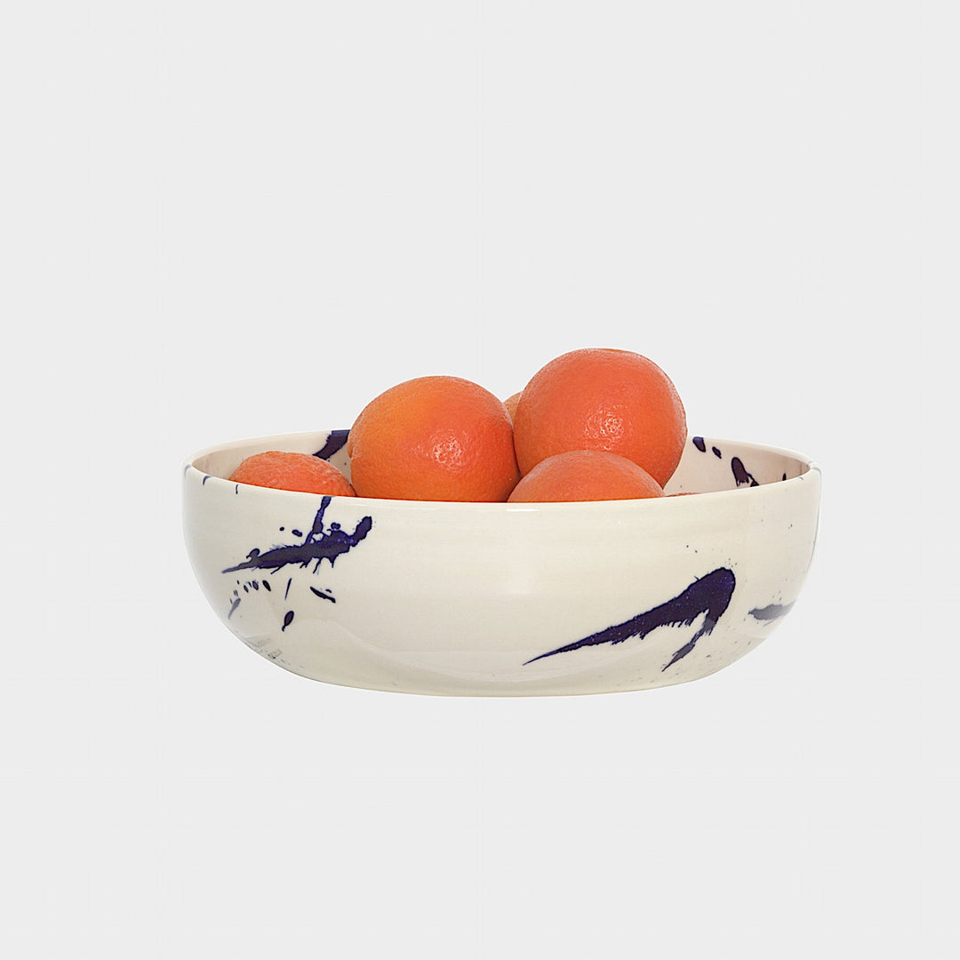 The Earl Home SERVING Bowl is a hand-thrown ceramic piece featuring a white interior and terracotta exterior with elegant swirl patterns. It is dishwasher and microwave safe.