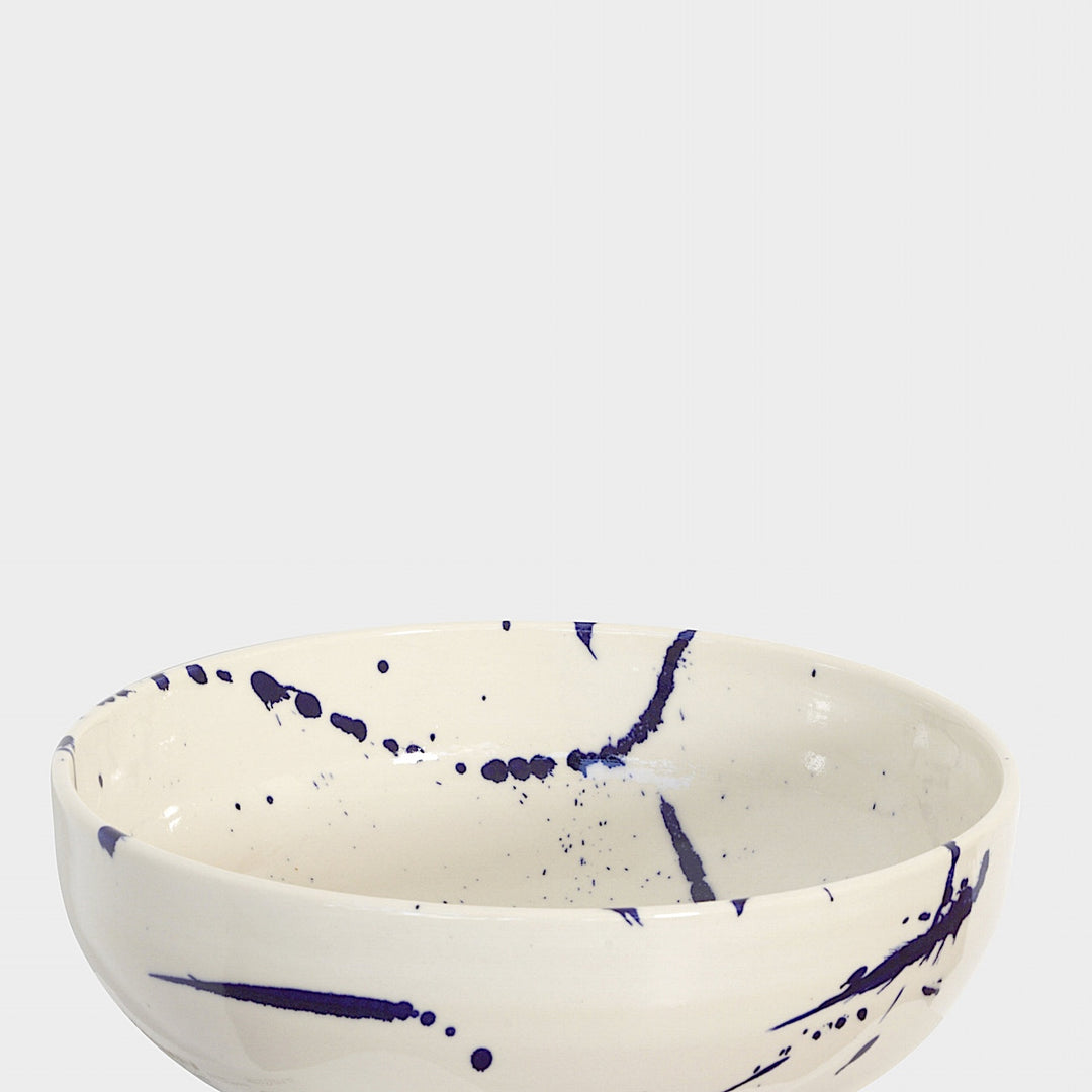 The Earl Home SERVING Bowl is a hand-thrown ceramic piece featuring a white interior and terracotta exterior with elegant swirl patterns. It is dishwasher and microwave safe.