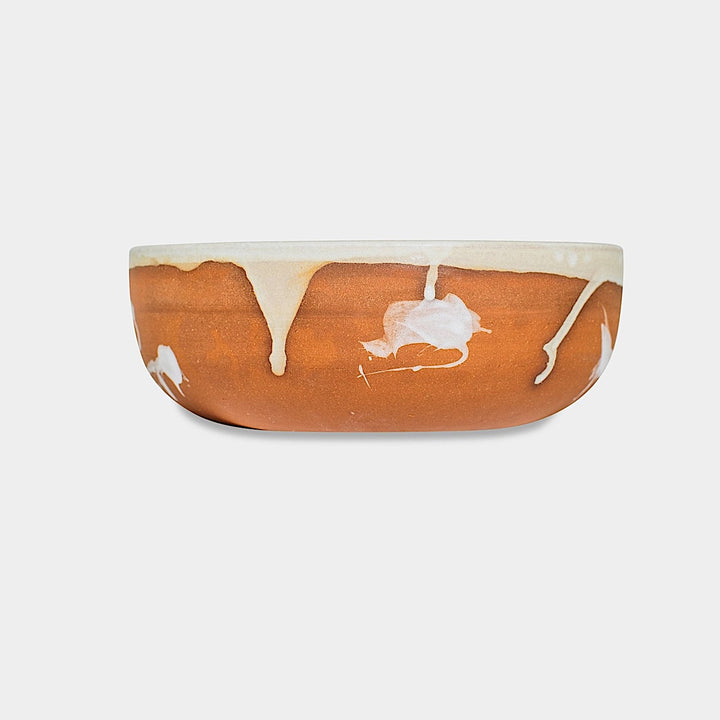 The Earl Home CEREAL Bowl features a white ceramic design with a black abstract splatter, set against a plain background. Microwave and dishwasher safe, it blends artistry and functionality for everyday use.