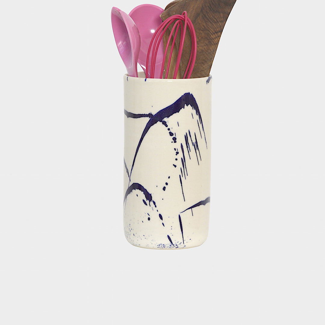 The TALL Cylinder cup by Earl Home features meticulous artistry with its hand-thrown white ceramic and abstract blue brushstrokes against a plain white background.