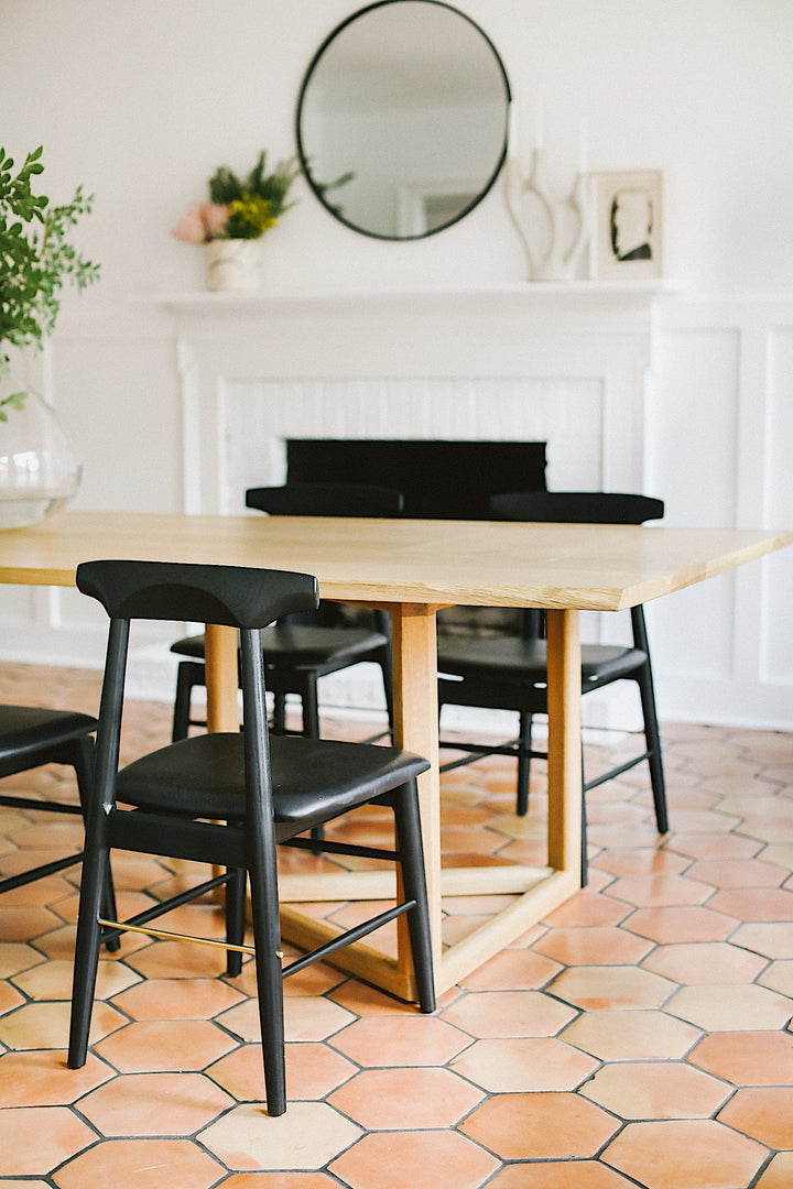 The WOLF Dining Table by Earl Home features a long, oval solid wood design with two geometric rectangular legs, elegantly displayed on a white background to highlight the beauty of unique wood furniture.