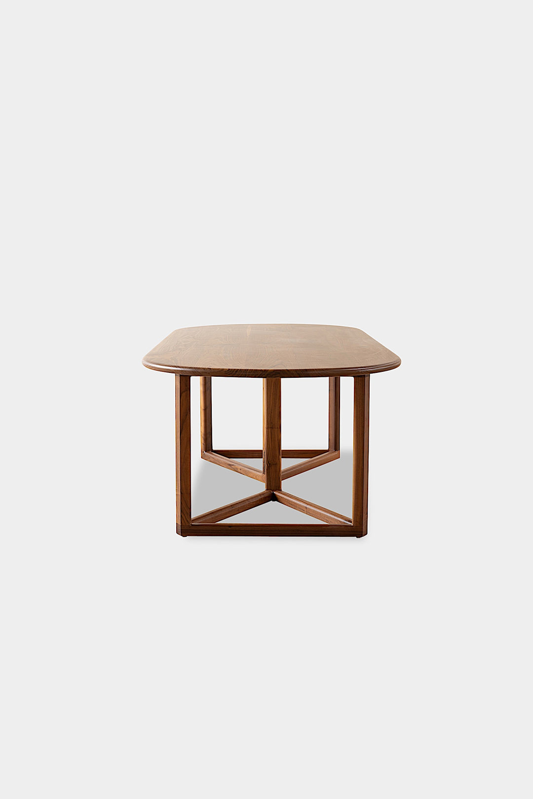 The WOLF Dining Table by Earl Home features a long, oval solid wood design with two geometric rectangular legs, elegantly displayed on a white background to highlight the beauty of unique wood furniture.