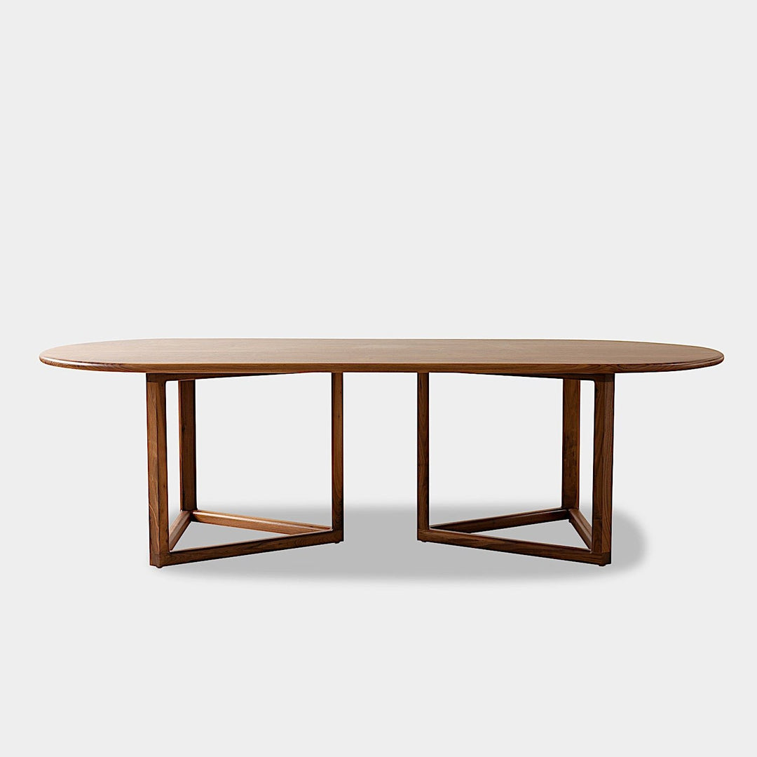 The WOLF Dining Table by Earl Home features a long, oval solid wood design with two geometric rectangular legs, elegantly displayed on a white background to highlight the beauty of unique wood furniture.