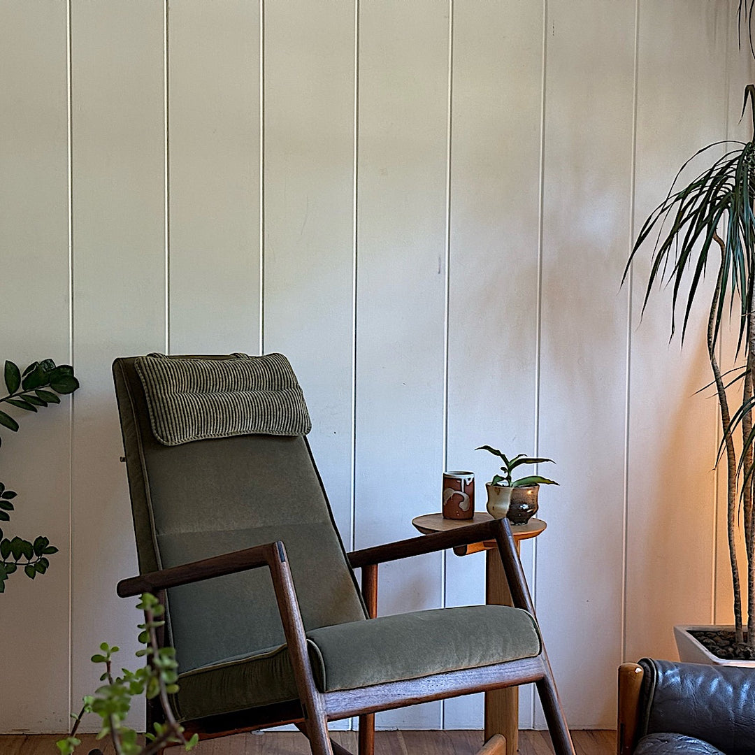 Side view of the Walnut MORESBY Rocker by Earl Home, featuring a green upholstered seat with a cushion, solid wood frame, and armrests against a white background.