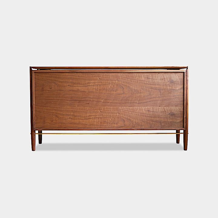 The KABOT Sideboard (Low) by Earl Home is a wooden mid-century modern dresser, featuring two woven panels and slender legs, exemplifying heritage quality design.