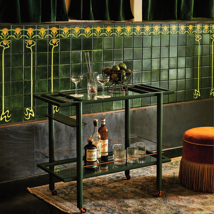 This bespoke BAR Cart from Earl Home is a solid wood bar cart on wheels with exquisite hand-cut joinery, featuring two shelves: a robust tempered glass top and an elegant lower shelf made of clear or smoked tempered glass. This cart comes in walnut, white oak, ebonized oak, or lacquered in any pantone color. Brass, Copper and Aluminum are the metal types offered for detail.
