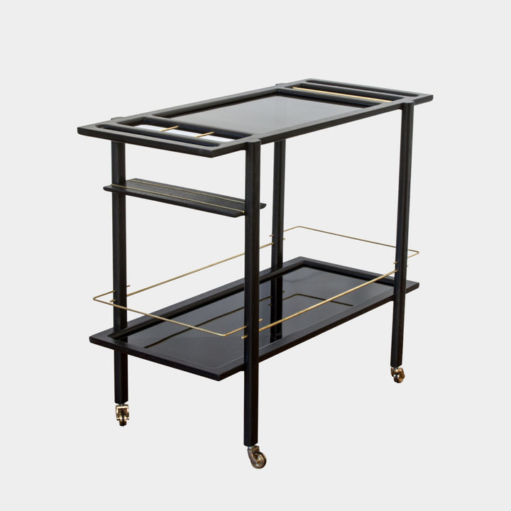 This bespoke BAR Cart from Earl Home is a custom hand made solid wood bar cart on wheels with exquisite hand-cut joinery, featuring two shelves: a robust tempered glass top and an elegant lower shelf made of clear or smoked tempered glass. This cart comes in walnut, white oak, ebonized oak, or lacquered in any pantone color. Brass, Copper and Aluminum are the metal types offered for detail.