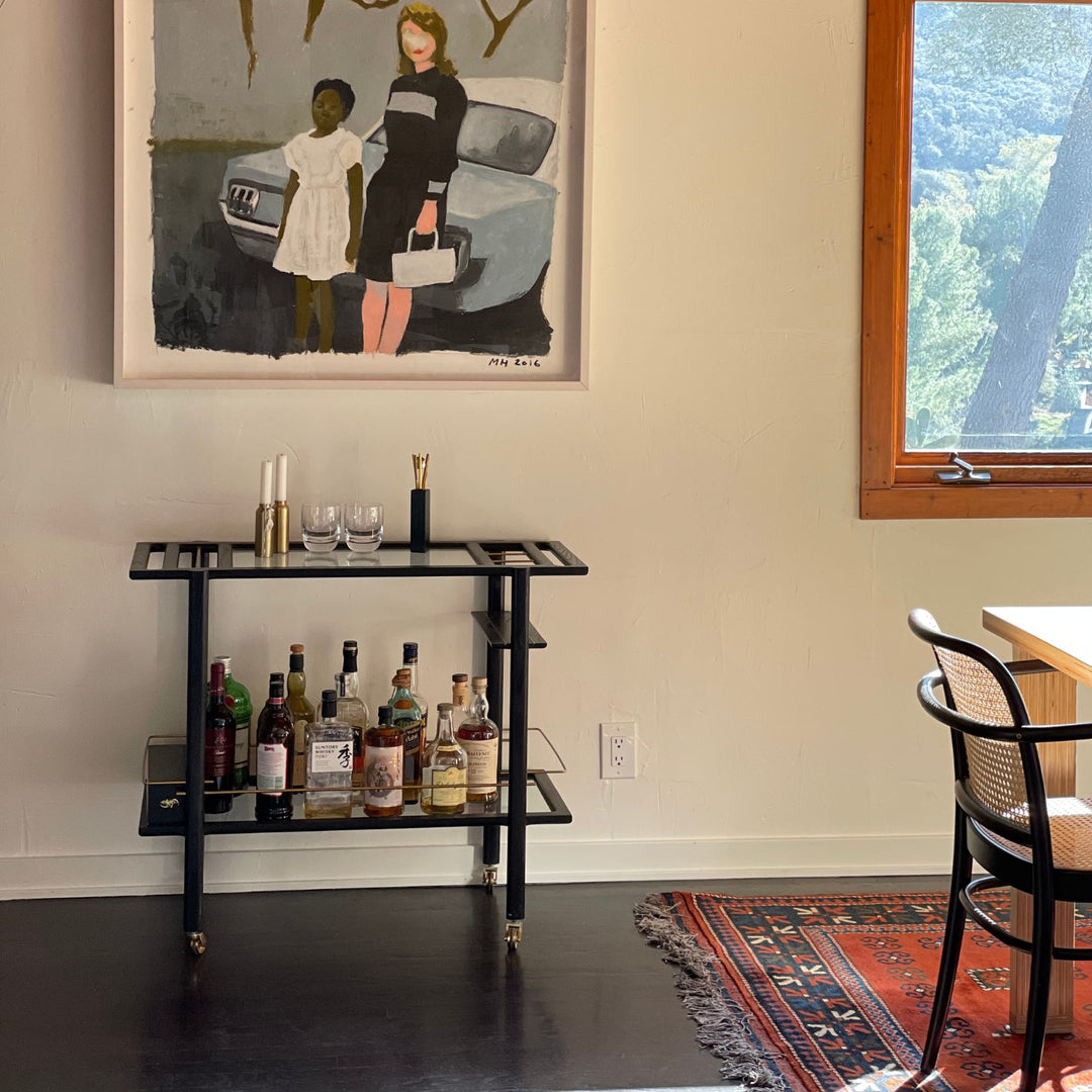 This bespoke BAR Cart from Earl Home is a custom hand made solid wood bar cart on wheels with exquisite hand-cut joinery, featuring two shelves: a robust tempered glass top and an elegant lower shelf made of clear or smoked tempered glass. This cart comes in walnut, white oak, ebonized oak, or lacquered in any pantone color. Brass, Copper and Aluminum are the metal types offered for detail.