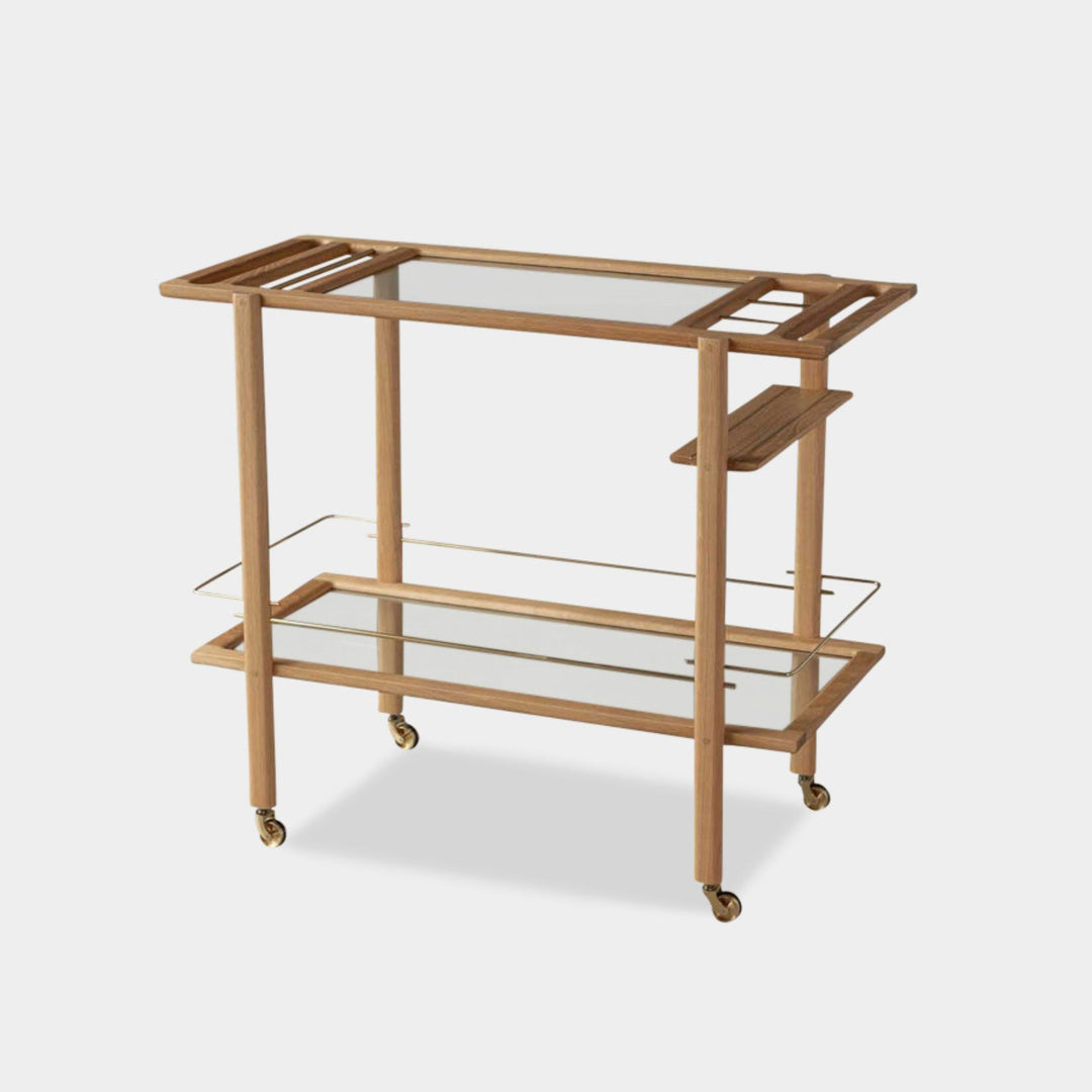 This bespoke BAR Cart from Earl Home is a custom hand made solid wood bar cart on wheels with exquisite hand-cut joinery, featuring two shelves: a robust tempered glass top and an elegant lower shelf made of clear or smoked tempered glass. This cart comes in walnut, white oak, ebonized oak, or lacquered in any pantone color. Brass, Copper and Aluminum are the metal types offered for detail.