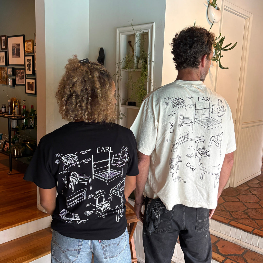 Two people standing in a room with a decorative wall and framed pictures.