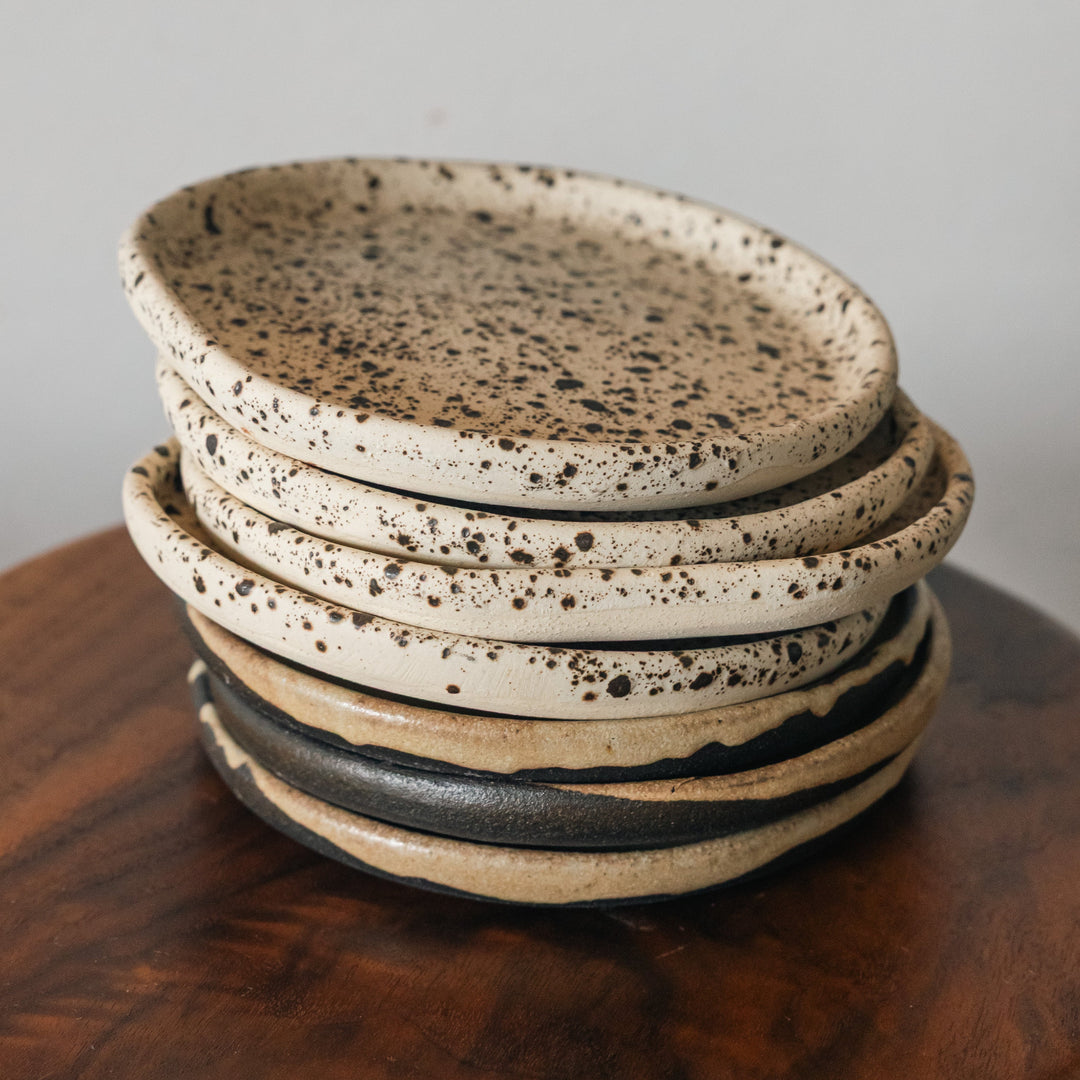 Stack of ceramic plates with speckled design on a wooden surface