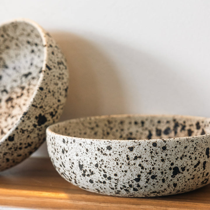 Speckled ceramic bowls on a wooden surface with a white background