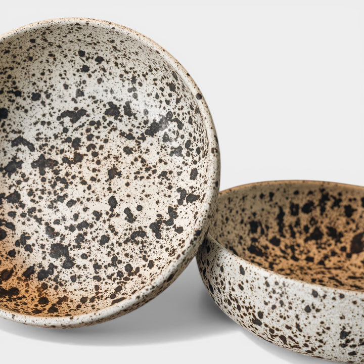 Two ceramic bowls with speckled patterns on a light gray background