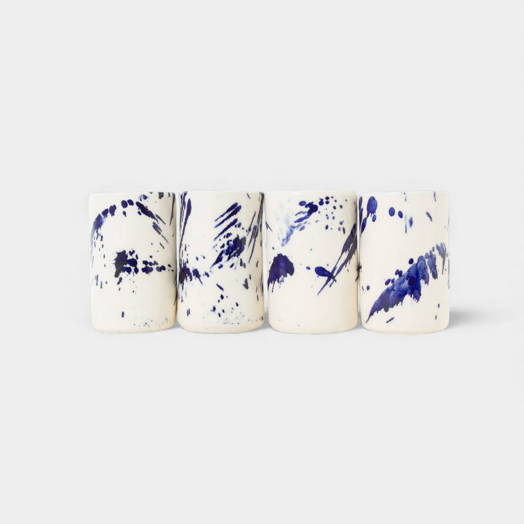 Four cylindrical cups with blue splatter abstract paint or glaze design. Hand thrown handmade pottery. Coffee Cup or mug perfect for cozy hygge morning. 