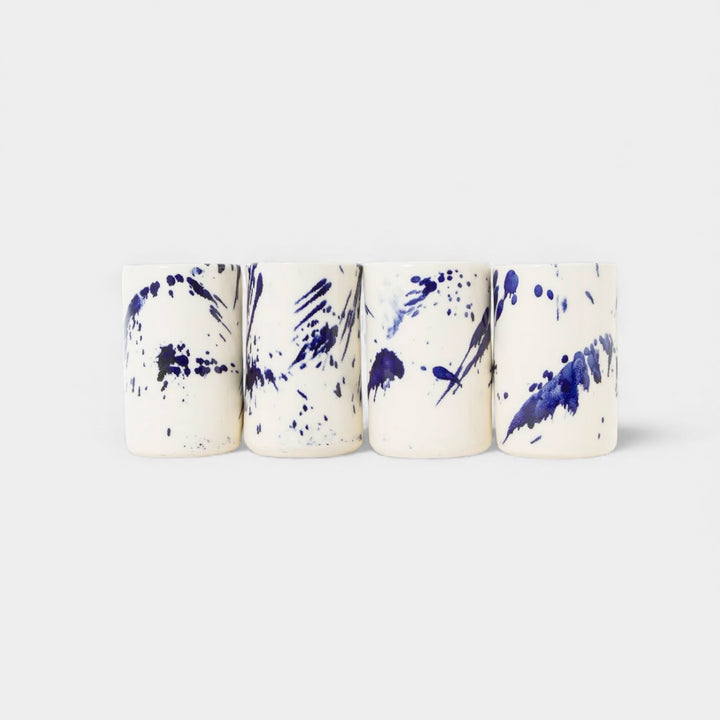 Four cylindrical cups with blue splatter abstract paint or glaze design. Hand thrown handmade pottery. Coffee Cup or mug perfect for cozy hygge morning. 