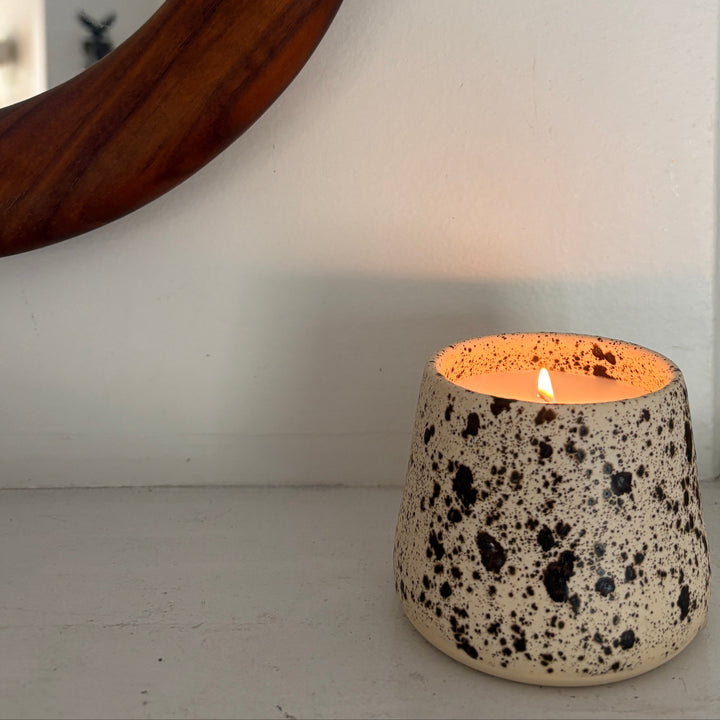 Speckled ceramic candle held by a hand with a plant in the background. Handmade in los Angeles, California. Made in America.
