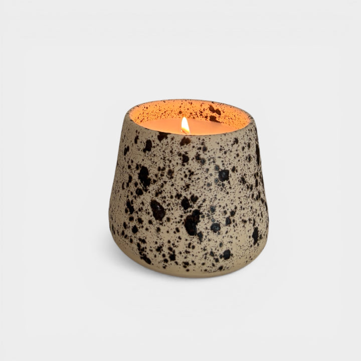 Speckled ceramic candle held by a hand with a plant in the background. Handmade in los Angeles, California. Made in America.