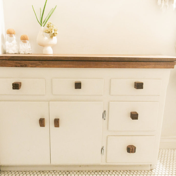 Bathroom vanity with white cabinets, wooden countertop, and decorative items showcasing custom wooden knobs