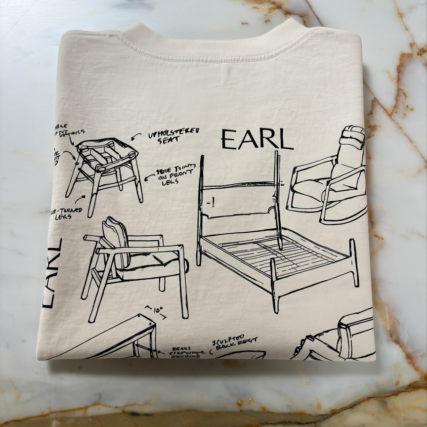 Folded beige sweatshirt with black line art and 'EARL' text on a marble surface