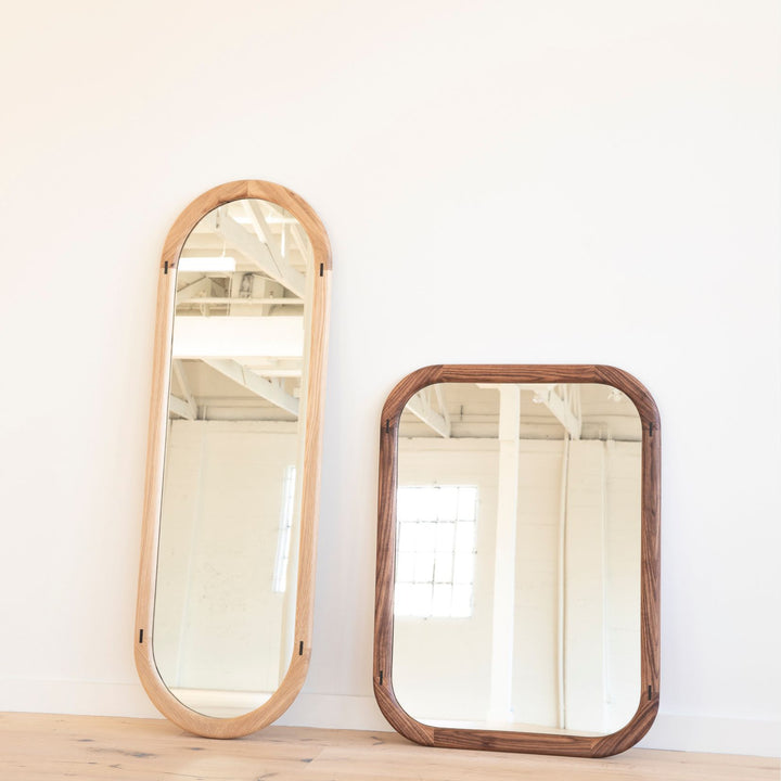 The HAROLD Mirror by Earl Home, a rectangular solid wood piece with metal inlay detailing, exquisitely reflects window light to enhance room brightness.