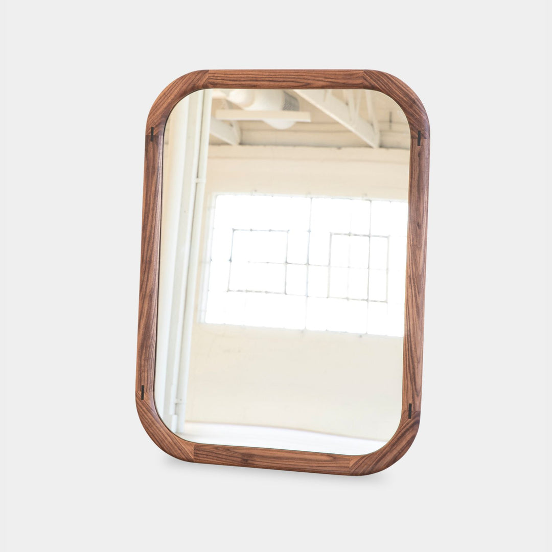 The HAROLD Mirror by Earl Home, a rectangular solid wood piece with metal inlay detailing, exquisitely reflects window light to enhance room brightness.