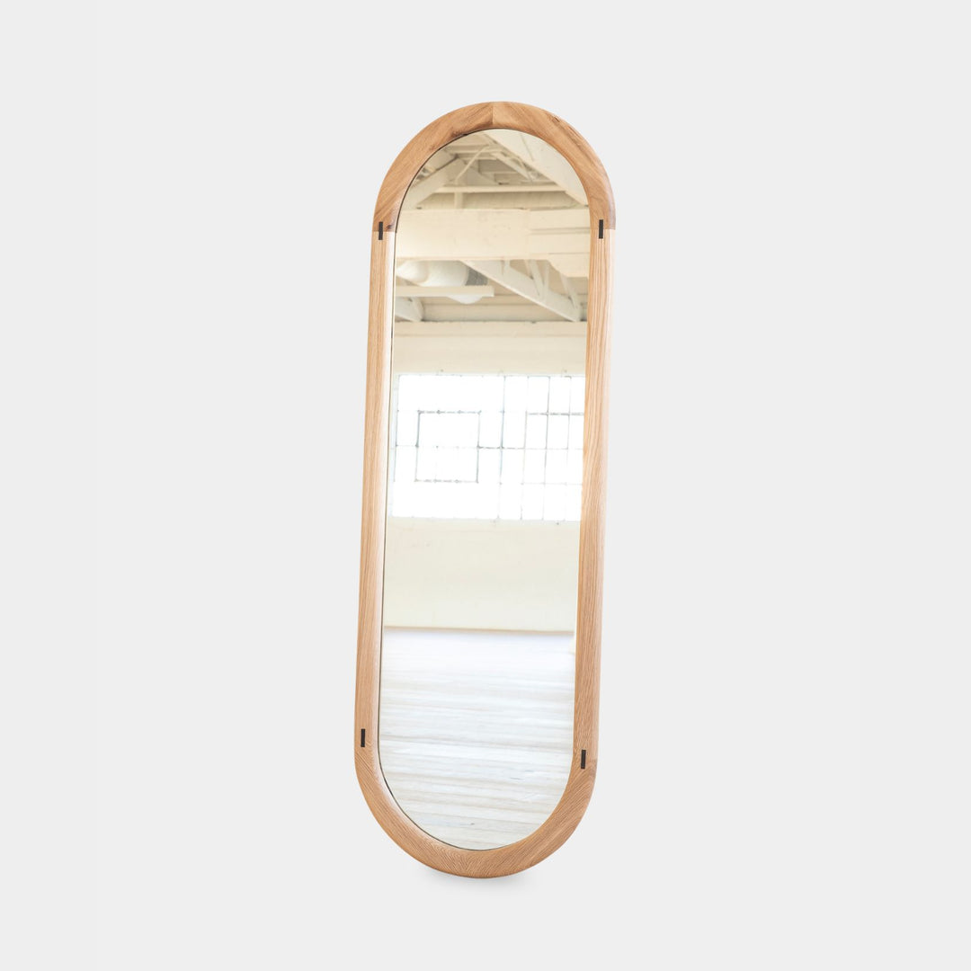 The HAROLD Mirror by Earl Home, a rectangular solid wood piece with metal inlay detailing, exquisitely reflects window light to enhance room brightness.