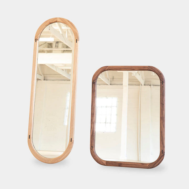 The HAROLD Mirror by Earl Home, a rectangular solid wood piece with metal inlay detailing, exquisitely reflects window light to enhance room brightness.