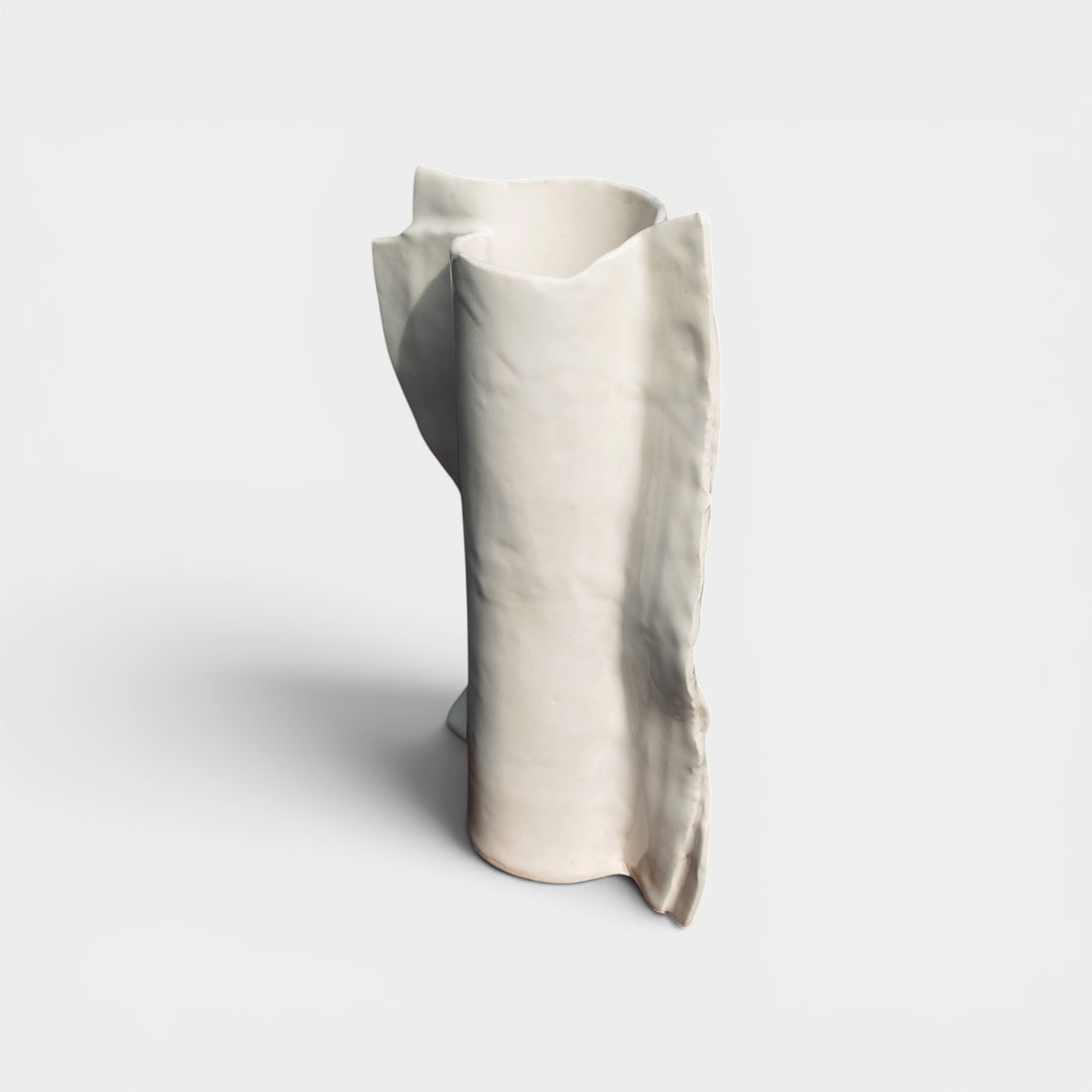 White marble vase on a light gray background. Beige or ivory ceramic vase in high gloss with dried plants and flowers on a wooden vintage chair against a gray lime wash wall with an ornate floral mirror.