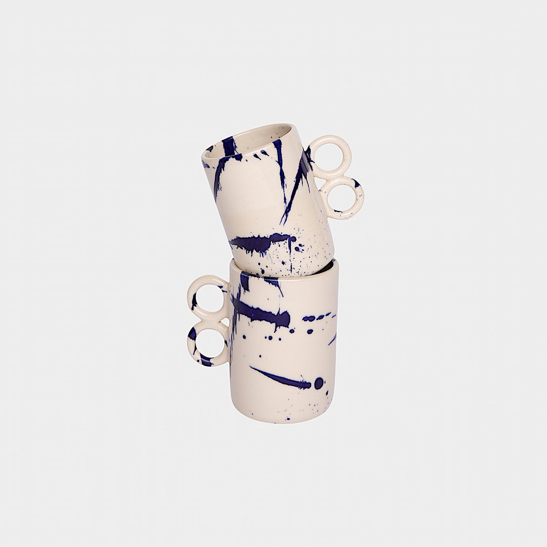 The Earl Home DOUBLE Handle Mug set includes two brown ceramic mugs, each featuring a unique round handle and white abstract patterns. Hand-thrown for artisanal charm, these mugs are perfect for those who appreciate the delicate artistry of ceramic craftsmanship.