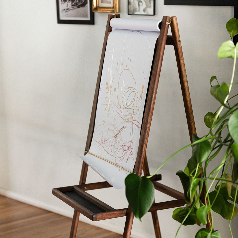 The KIDS Easel by Earl Home is a freestanding kids' easel made from sustainably sourced hardwood, featuring a chalkboard surface and a paper roll at the top. Available in ebonized oak, walnut or white oak.