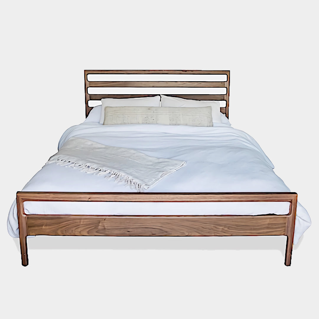 The LAMEL Bed by Earl Home is a hand-crafted bed frame with solid wood construction and a slatted headboard. It pairs beautifully with white pillows and a striped duvet, offering style and comfort. Available in custom bed sizes to fit your space perfectly.