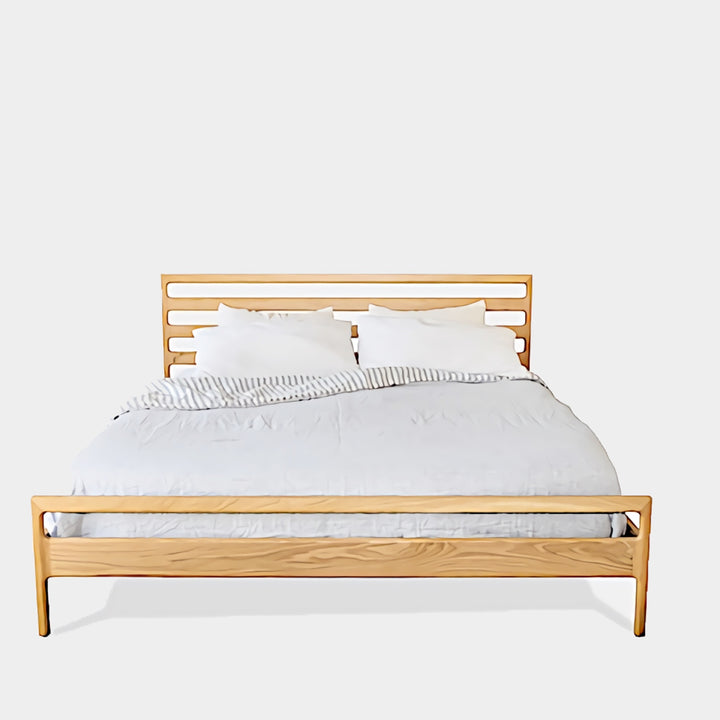 The LAMEL Bed by Earl Home is a hand-crafted bed frame with solid wood construction and a slatted headboard. It pairs beautifully with white pillows and a striped duvet, offering style and comfort. Available in custom bed sizes to fit your space perfectly.