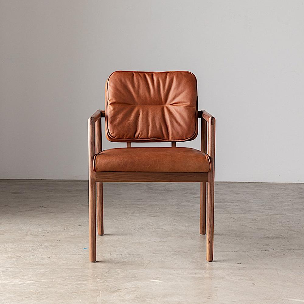 The MORESBY Captain Chair by Earl Home is hand-made with a custom upholstered seat in rich brown leather and solid wood, set against a white background.