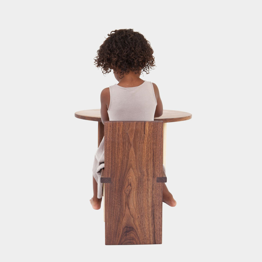 The Earl Home KIDS Set, featuring a custom, round wooden table made from sustainably sourced American hardwood. Two rectangular chairs are ideally positioned on opposite sides for a kid's table setup. Walnut mixed with maple, solid walnut, solid white oak, ebonized oak are all options for this custom made to order set.
