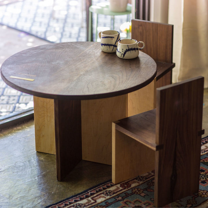 The Earl Home KIDS Set, featuring a custom, round wooden table made from sustainably sourced American hardwood. Two rectangular chairs are ideally positioned on opposite sides for a kid's table setup. Walnut mixed with maple, solid walnut, solid white oak, ebonized oak are all options for this custom made to order set.