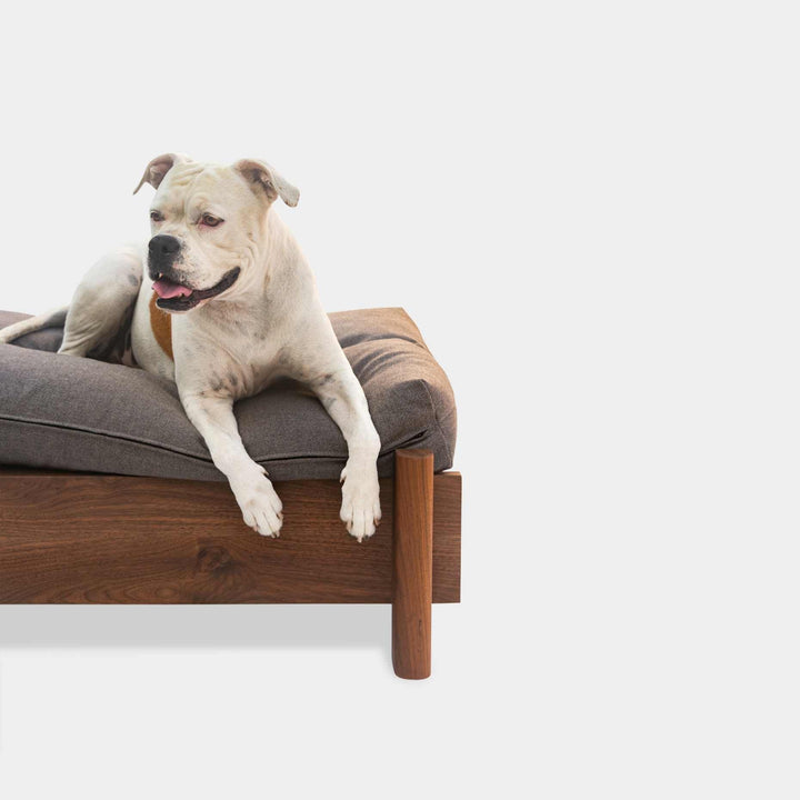 This EARL handmade dog bed has a solid wood base with a hidden drawer, and a custom detachable cushion upholstered in Sunbrella Blend Sand. We offer various fabrics and customers own fabric is encouraged as well. The base can be made in walnut, white oak, or ebonized oak and custom sizing is also available.