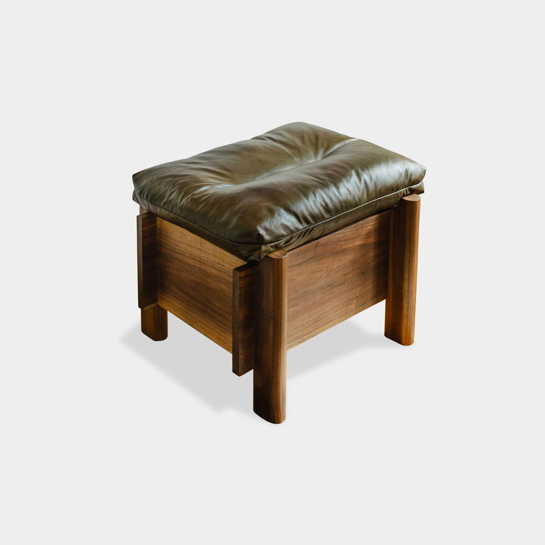 The LAPILO Ottoman by Earl Home is a stylish, handmade piece featuring a green cushioned top and offers storage seating against a white background.