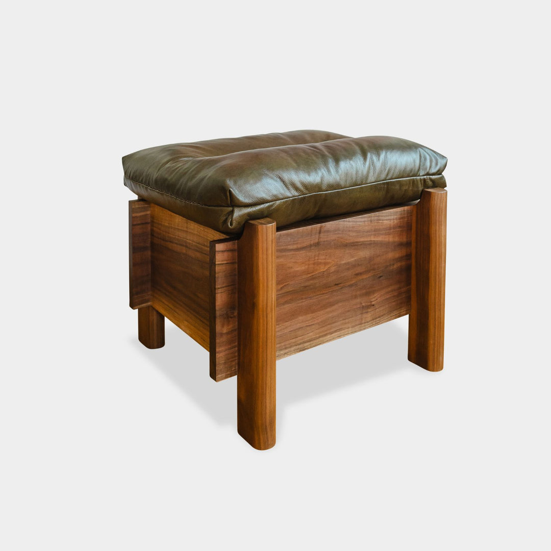 The LAPILO Ottoman by Earl Home is a stylish, handmade piece featuring a green cushioned top and offers storage seating against a white background.