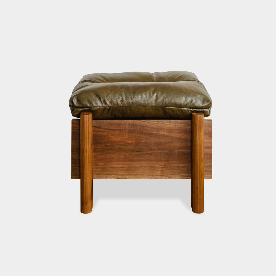 The LAPILO Ottoman by Earl Home is a stylish, handmade piece featuring a green cushioned top and offers storage seating against a white background.