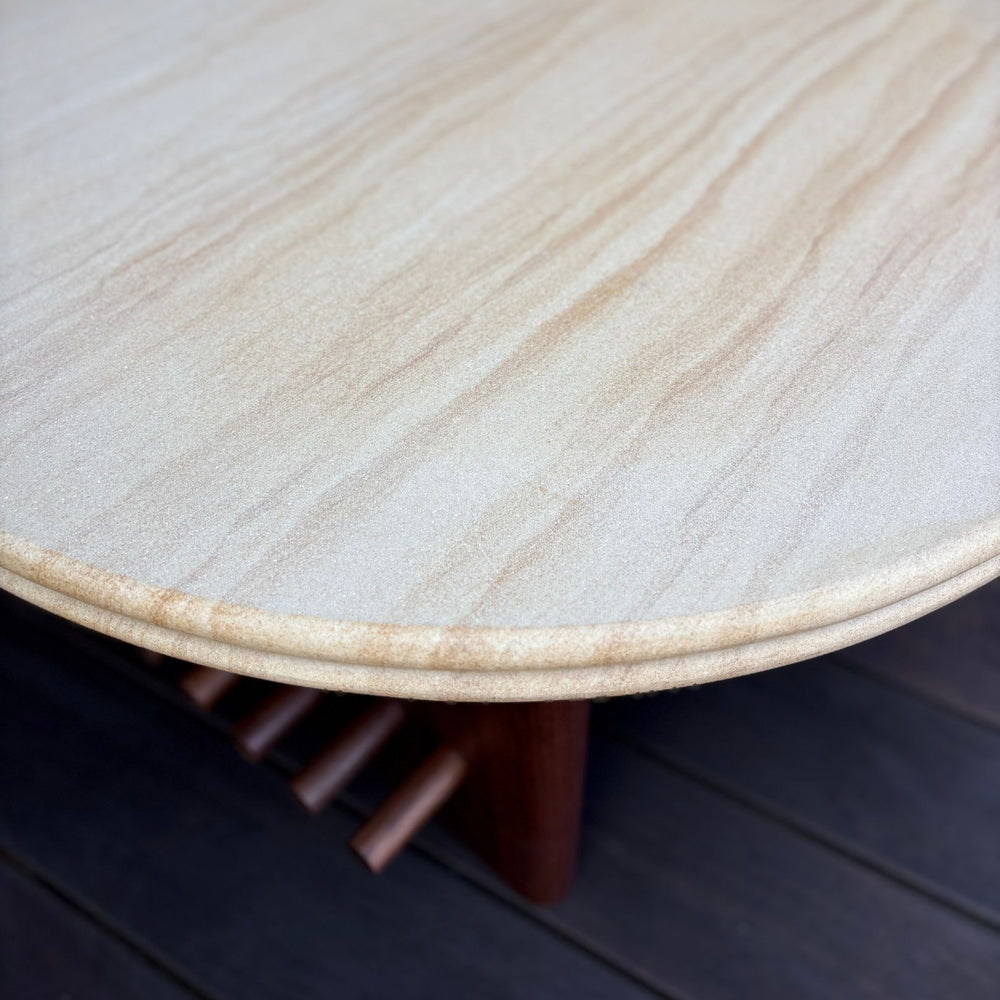 The sandstone circular coffee table, featuring a refined double bullnose edge, showcases the stone’s natural beauty while adding a soft, sculpted touch. 
Supporting this stunning round top is a sleek and sophisticated solid walnut base, meticulously crafted for both durability and style. 