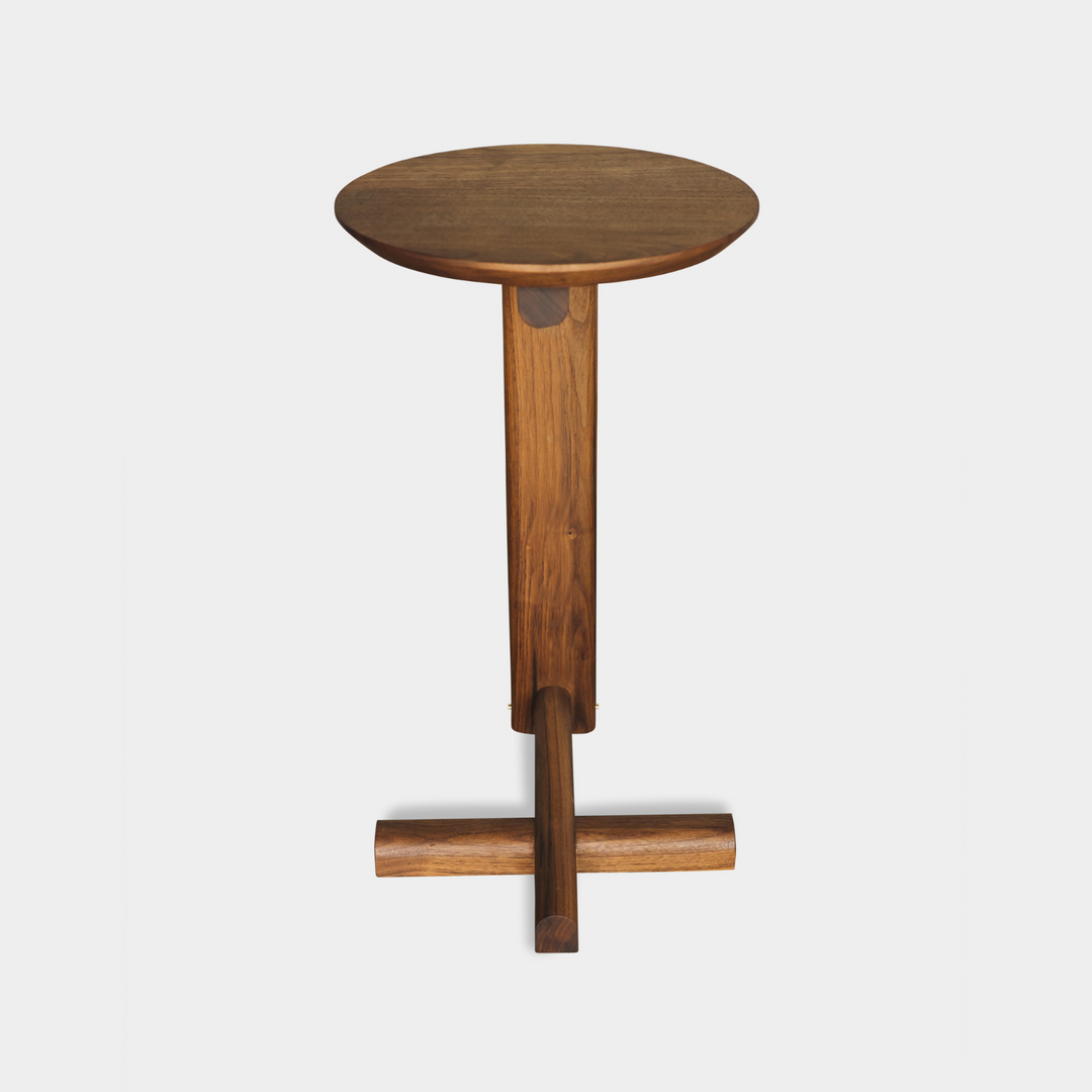 The Walnut MEDIA Side Table by Earl Home is a beautifully crafted nesting table featuring a solid wood construction with a round top and a custom-designed T-shaped base.