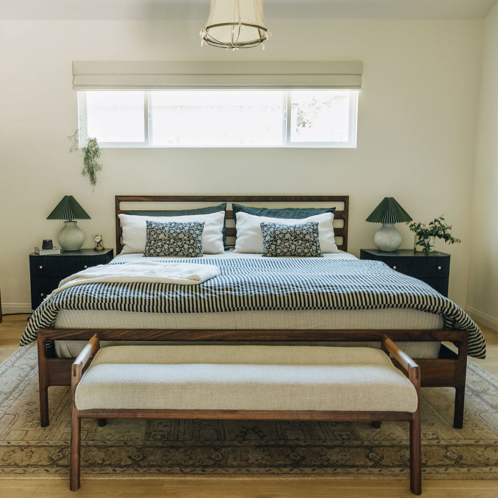 The Earl Home MORESBY Bench highlights a plush light cushion on a solid wood frame, featuring clean lines and a minimalist design. Available in Walnut, Ebonized Oak, or White Oak with a custom upholstered cushion.