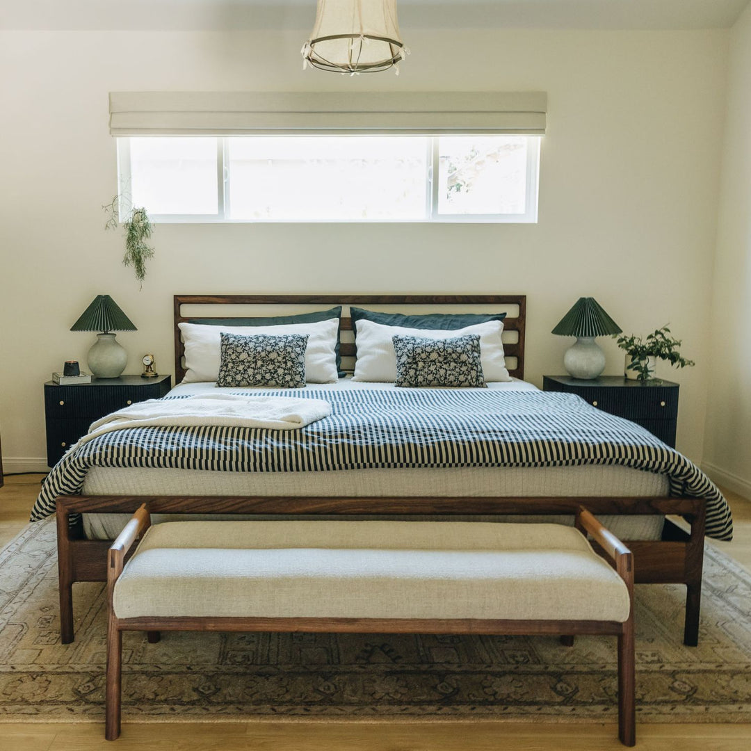 The Earl Home MORESBY Bench highlights a plush light cushion on a solid wood frame, featuring clean lines and a minimalist design. Available in Walnut, Ebonized Oak, or White Oak with a custom upholstered cushion.