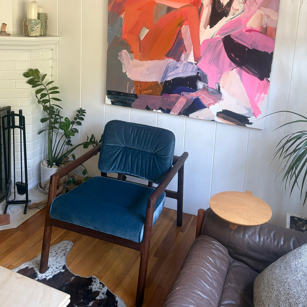 Living room  designed with a blue velvet MORESBY lounge chair, and styles well with abstract paintings. Also available with a walnut or white oak frame.