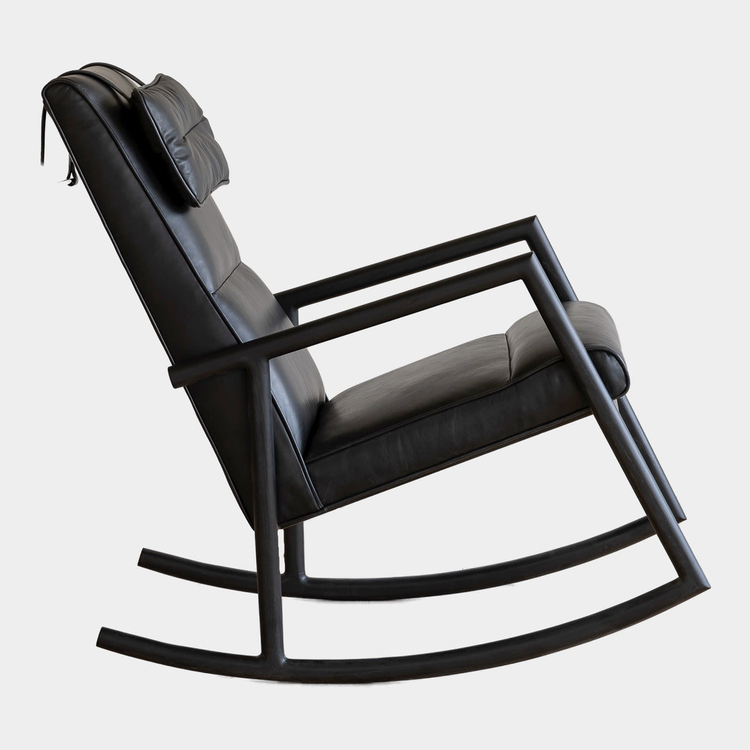 Side view of the MORESBY Rocker by Earl Home. This handmade wooden rocking chair features solid wood construction, black leather cushions, a custom upholstered seat, and an attached headrest.