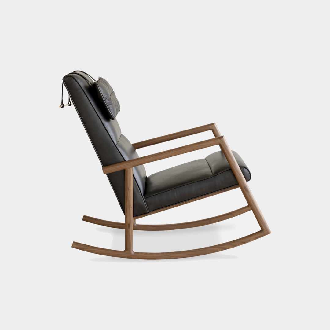 Side view of the MORESBY Rocker by Earl Home. This handmade wooden rocking chair features solid wood construction, black leather cushions, a custom upholstered seat, and an attached headrest.