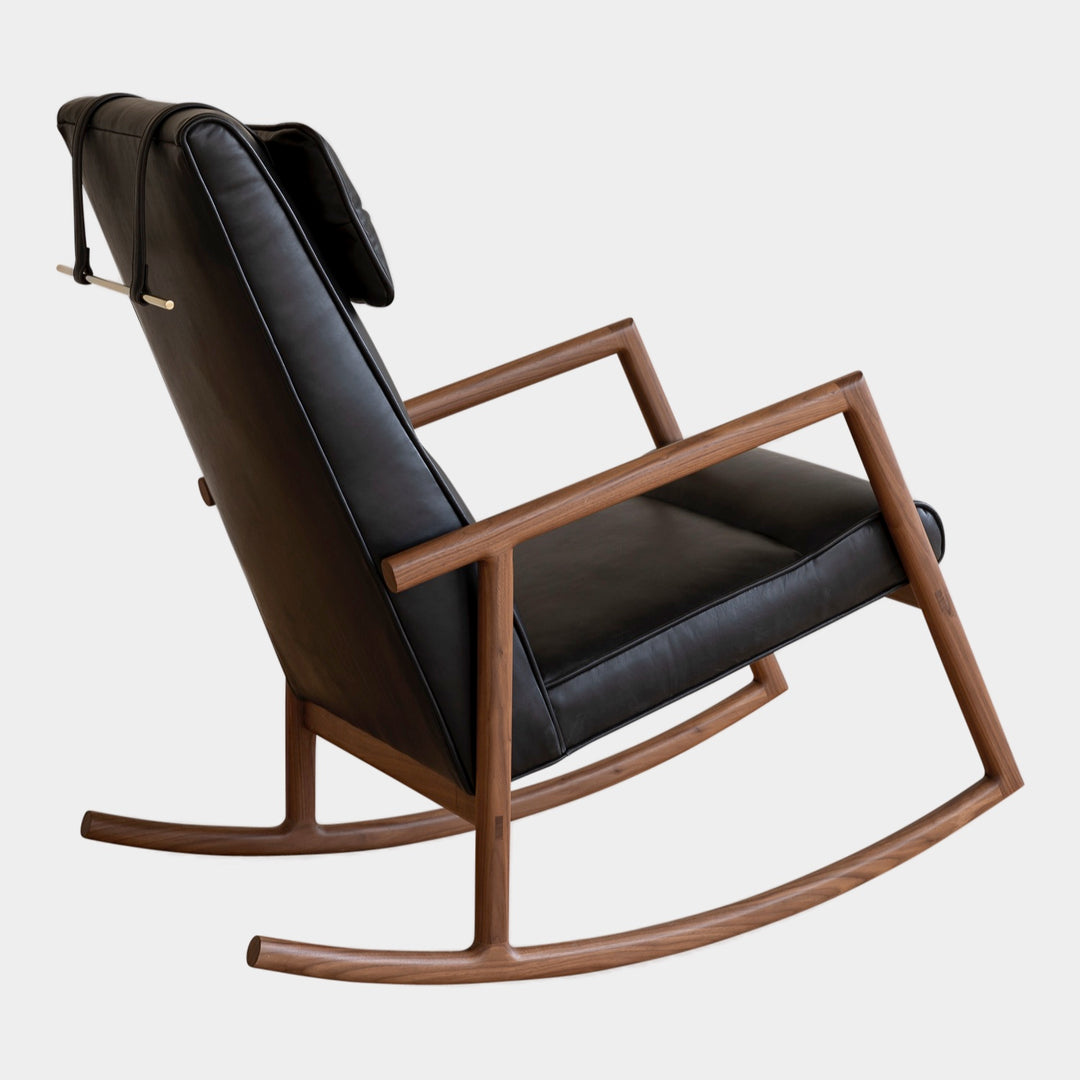 Side view of the MORESBY Rocker by Earl Home. This handmade wooden rocking chair features solid wood construction, black leather cushions, a custom upholstered seat, and an attached headrest.