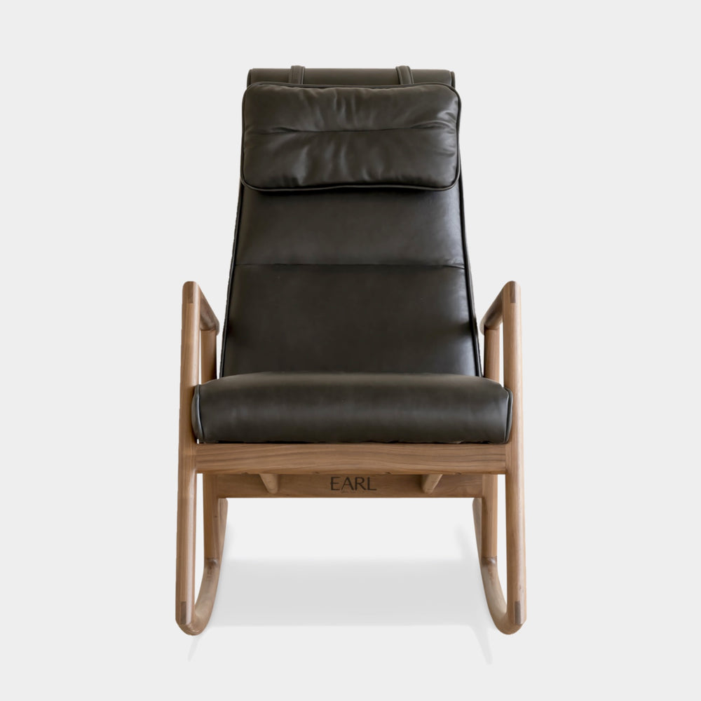 Side view of the MORESBY Rocker by Earl Home. This handmade wooden rocking chair features solid wood construction, black leather cushions, a custom upholstered seat, and an attached headrest.